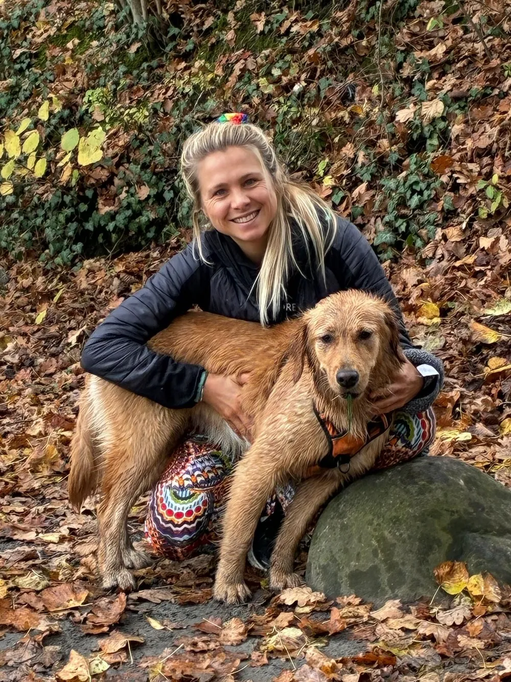 Olivia, vétérinaire, accroupie dans les feuilles d'automne, un chien au pelage doré contre elle
